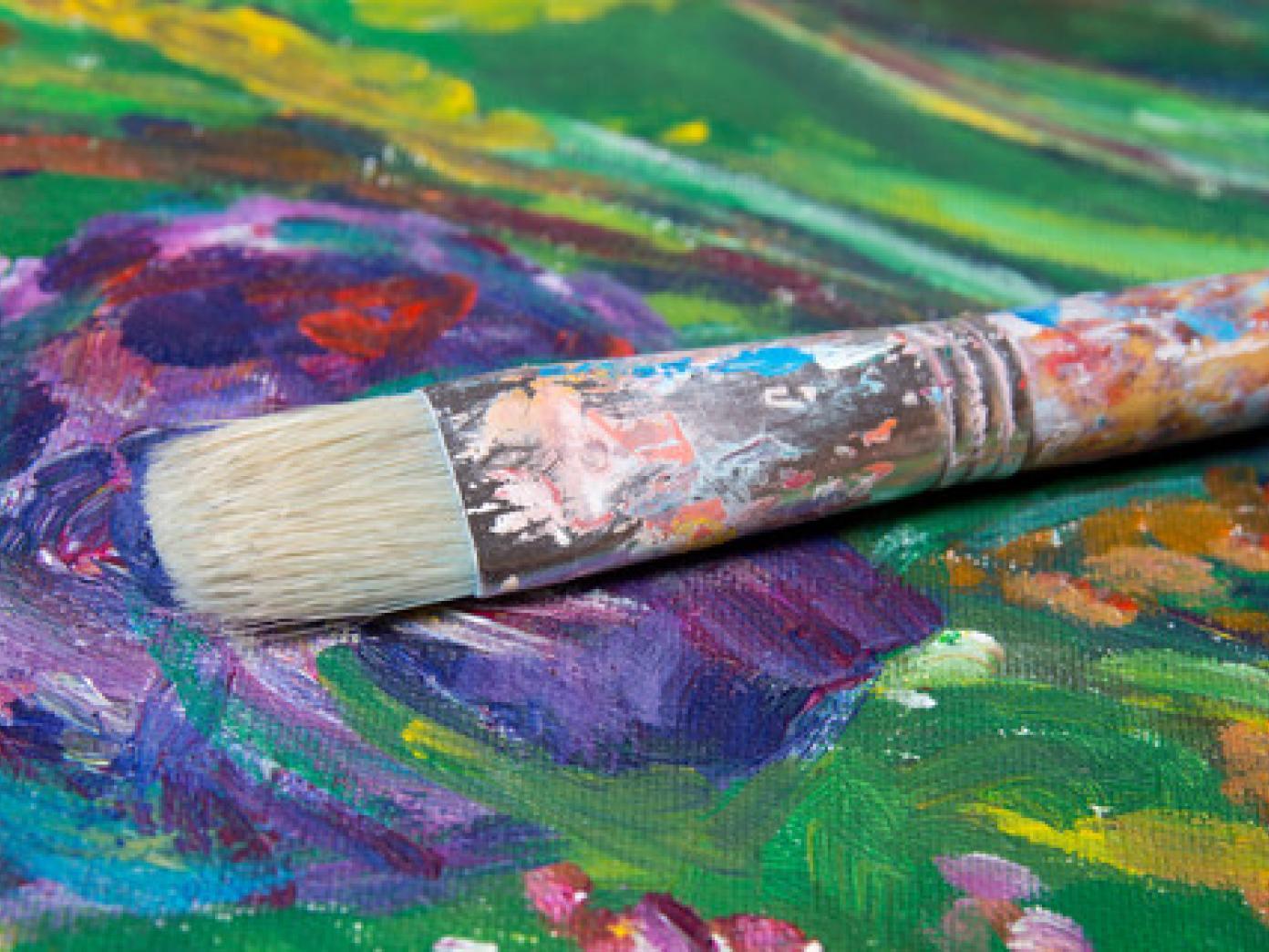 Nærbillede af et maleri i flere farver med en pensel ovenpå.