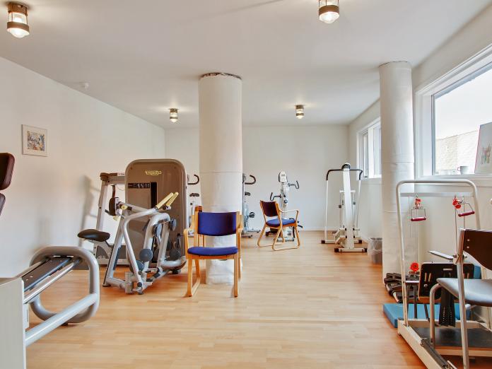Lyst motionsrum med forskellige træningsmaskiner.