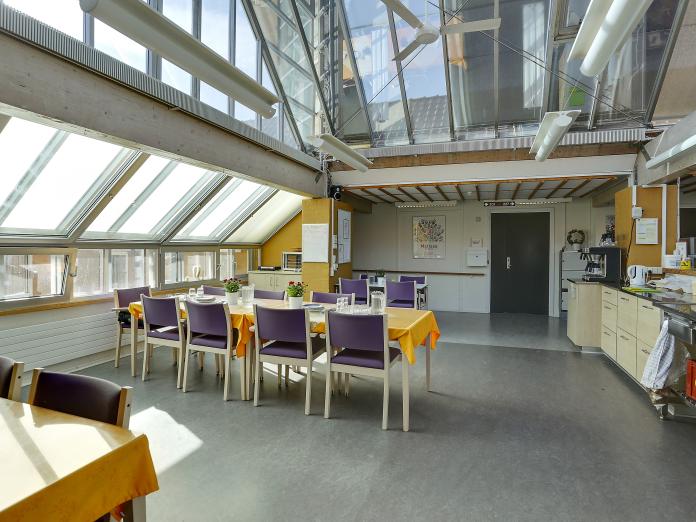 Fællesområde med glastag. Rummet er indrettet med langborde og stole samt et kantineområde.
