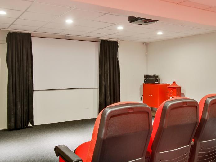 Rum indrettet som biograf med lærred og røde biografstole.