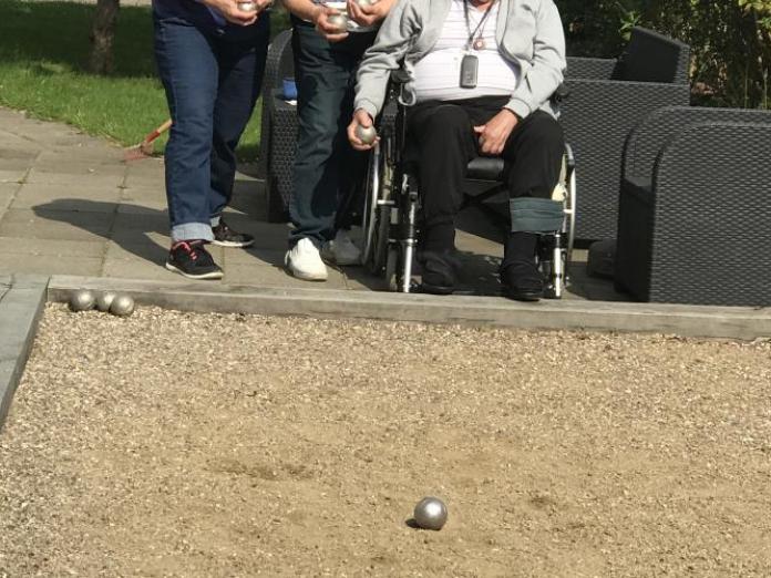 Tre personer spiller petanque på en udendørs petanquebane.