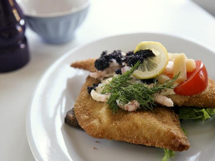 Tallerken med højtbelagt smørrebrød med fiskefilet, rejer, asparges, dild og tomater.