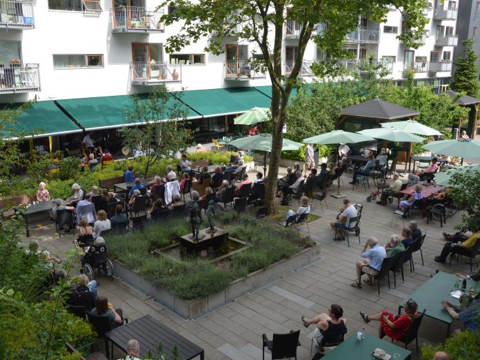 Fælledgårdens have under jazzfestival i København. Der er mange tilskuere til en scene med live jazzmusik.